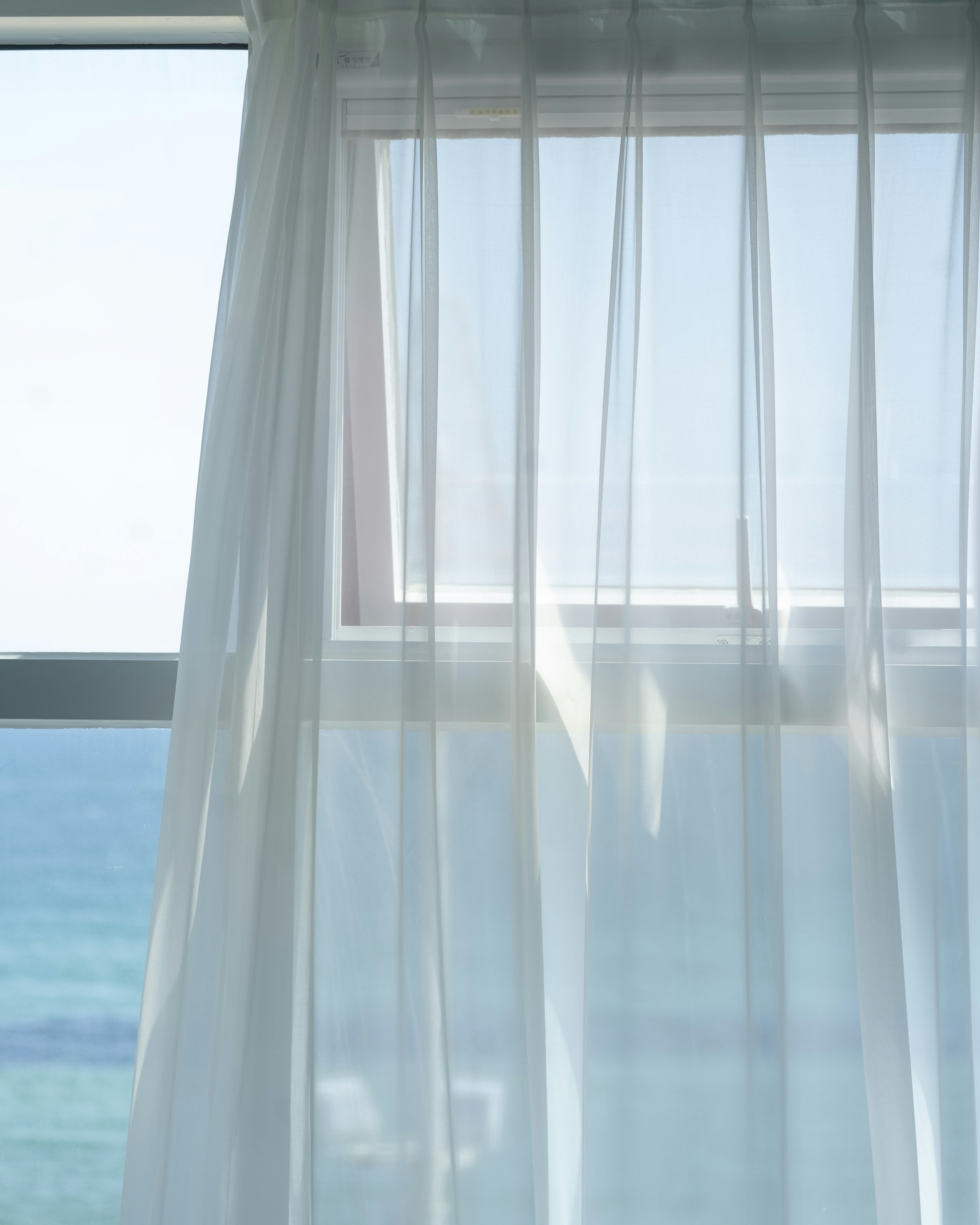 海の見える窓と、光を通す薄いカーテン