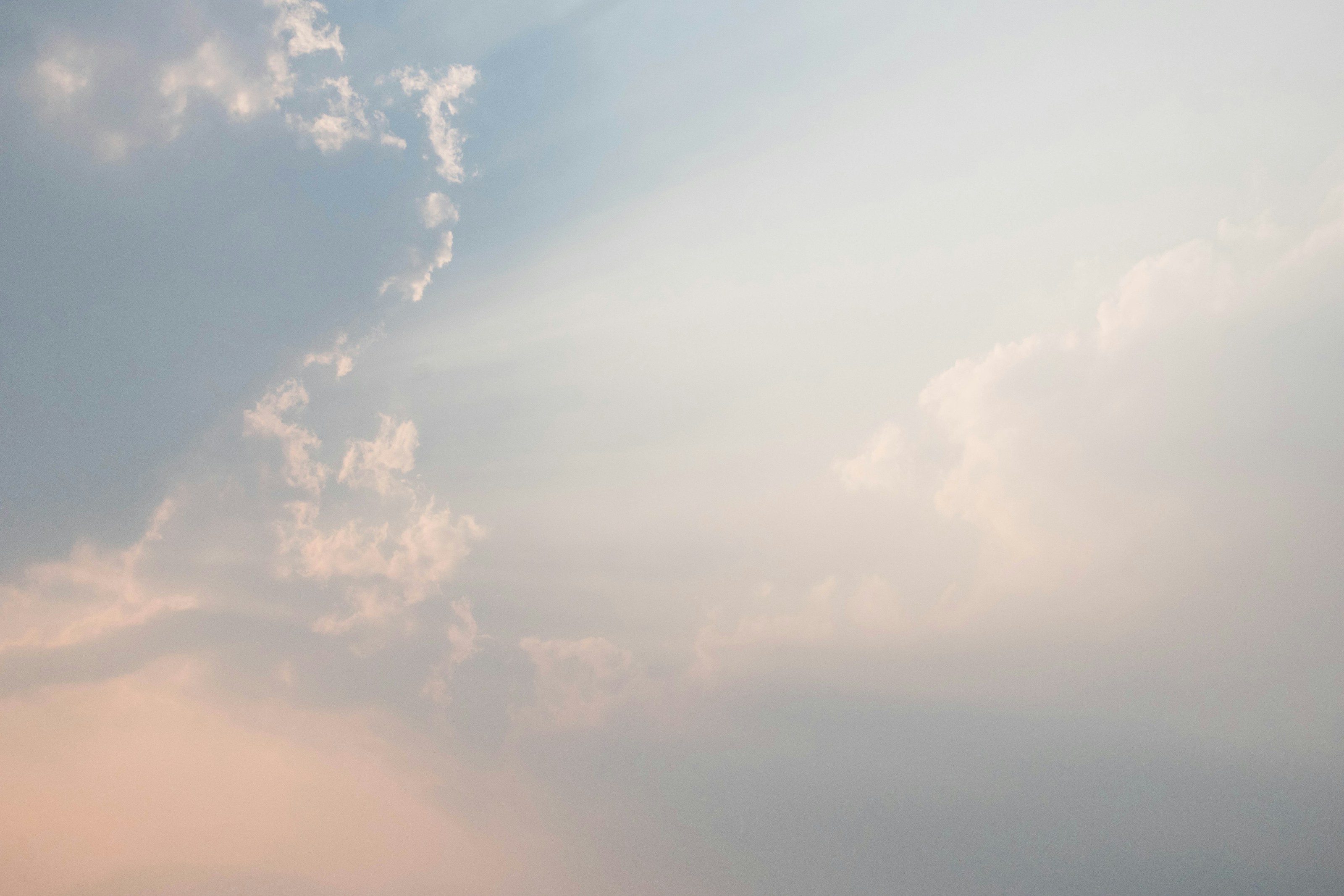 淡い空、雲の陰から広がる光の筋